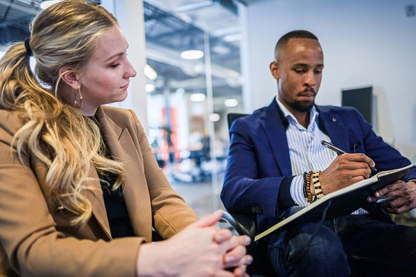 man taking notes with woman watching
